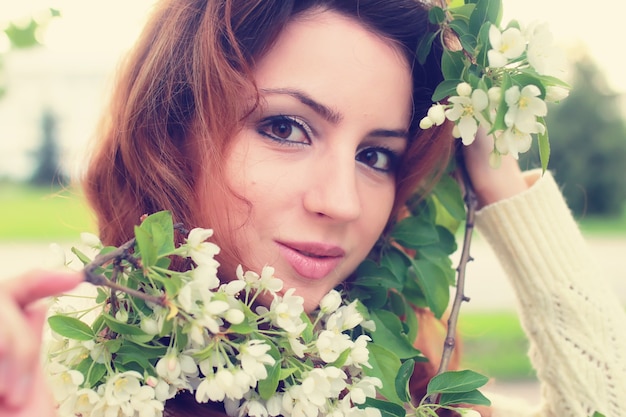 mujer de pelo rojo en rama de flor de manzana