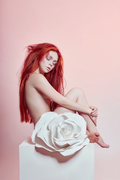 Mujer con pelo rojo sentada flor de papel grande