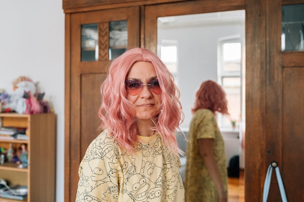 Una mujer de pelo rosa se para frente a un espejo.