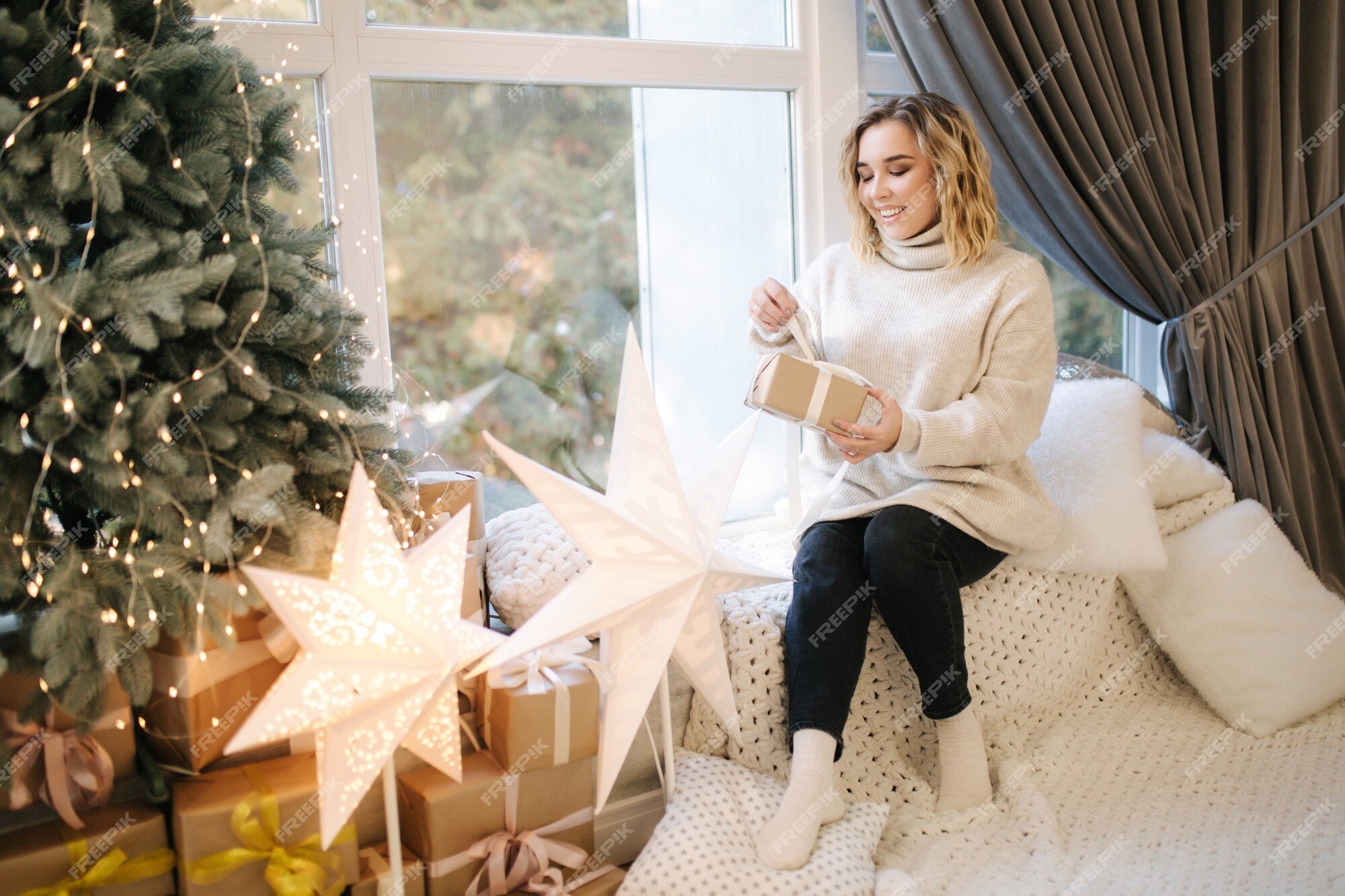 Mujer de pelo rubio en con abierta presente en tiempo de navidad. stand de mujer elegante por gran árbol navidad | Foto Premium