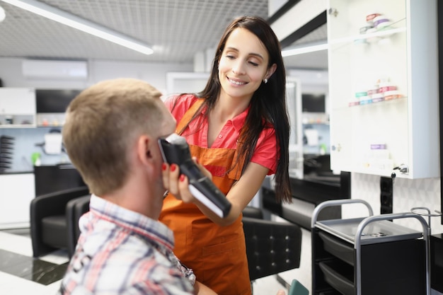 Mujer peluquera crea un corte de pelo usando una máquina de afeitar eléctrica en un salón de belleza