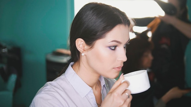 Mujer en la peluquería bebe café