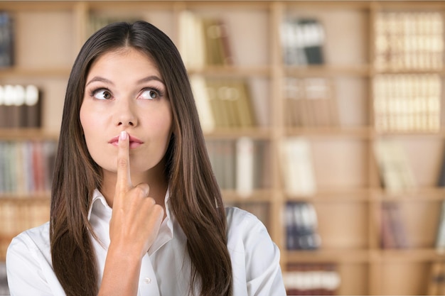 Mujer de pensamiento con el dedo en los labios mirando a un lado