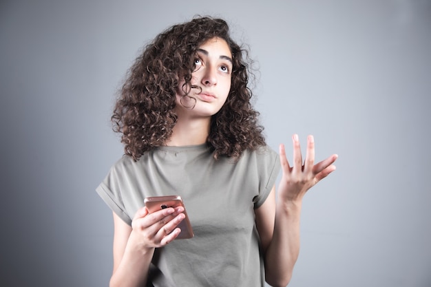 Mujer de pensamiento joven que sostiene el teléfono inteligente.