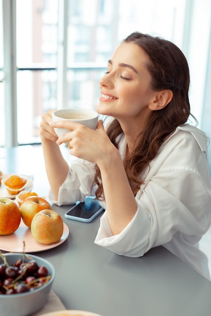 Mujer pensando en el día tomando café por la mañana