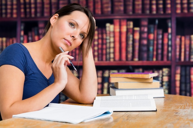 Foto mujer pensando con pluma y libro