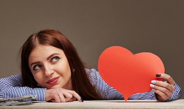 La mujer pensante joven en el fondo del estudio hace elección de vida amor o dinero, concepto de prioridades y metas de la vida