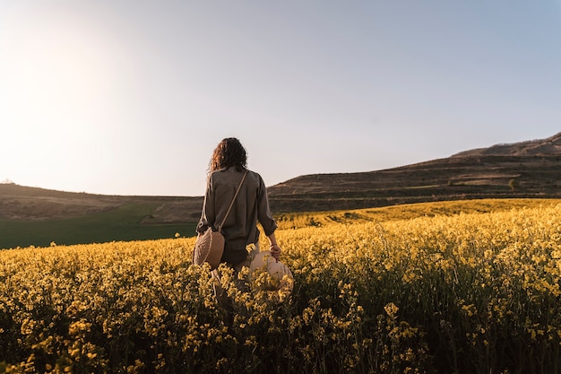 Foto mujer pensativa caminando entre flores en el campo. concepto de melancolía