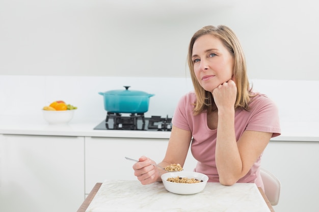 Mujer pensativa con cereales en la cocina