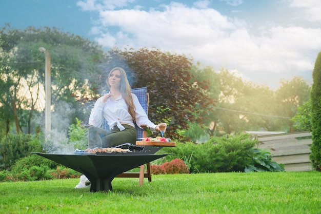 Mujer pensativa cocinando shashlik vegetariano en barbacoa