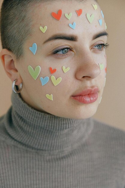 Foto mujer pensativa de la cosecha en cuello alto con corte de pelo corto y pegatinas multicolores en forma de corazones en fa