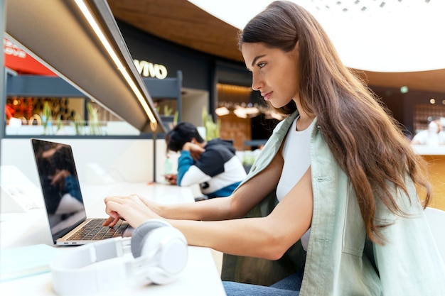 Foto mujer pensativa estudiando usando una computadora portátil sentada en el café. joven estudiante aprendiendo idioma