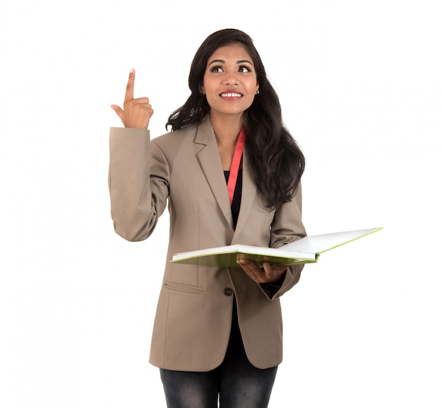 Mujer pensativa estudiante, maestra o mujer de negocios sosteniendo libros y mostrando un signo bien en el espacio en blanco