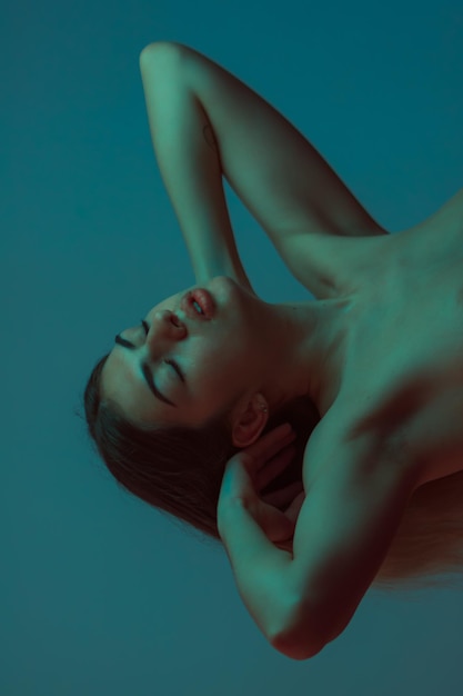 Foto mujer pensativa con los ojos cerrados contra un fondo azul
