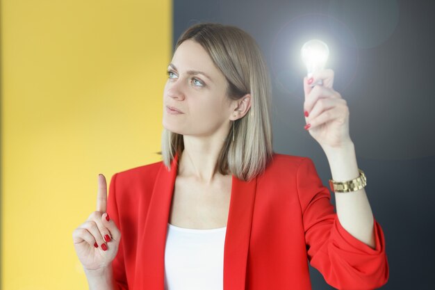 Foto mujer pensativa tiene bombilla en la mano. concepto de desarrollo de pequeñas y medianas empresas.