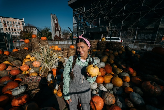 Mujer con una pequeña calabaza entre la cosecha de otoño.