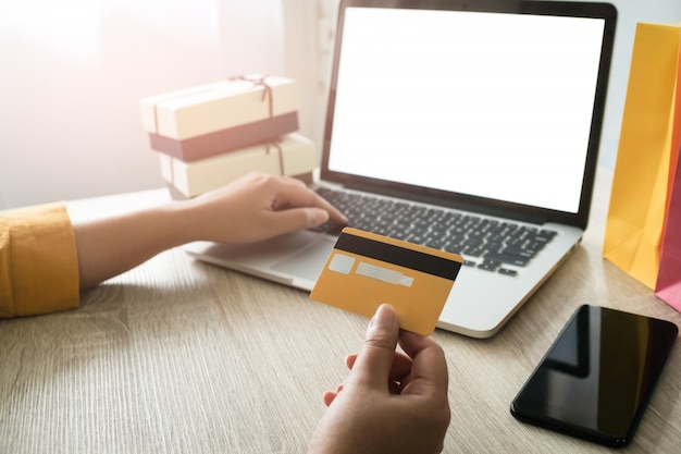 Mujer y pequeño carro de compras con ordenador portátil para el concepto de compras en línea por Internet