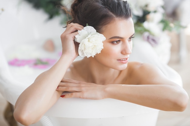 Mujer perfecta bañándose con flores y leche