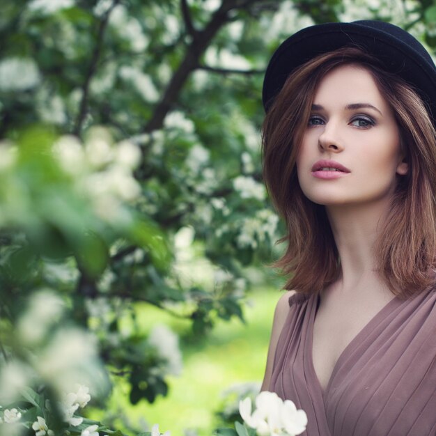 Mujer perfecta con flores en el parque de la primavera