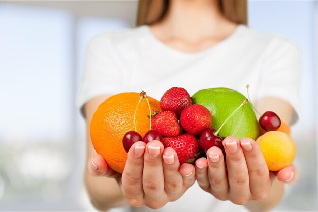 Mujer perfecta en ropa blanca con frutas en las manos