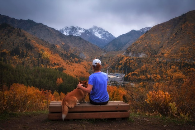 Una mujer con perro admira el paisaje montañoso otoñal del Medeo