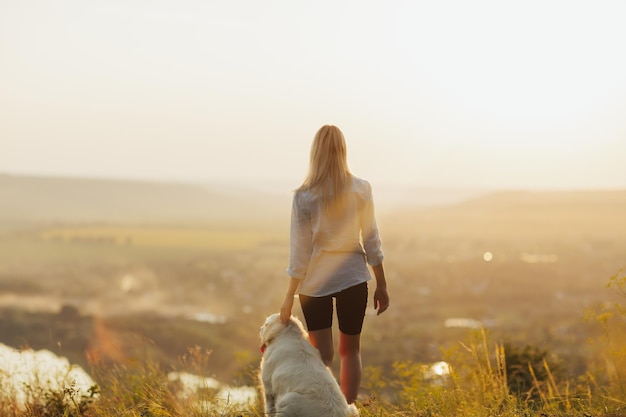 mujer y perro admirando la puesta de sol y el hermoso paisaje en la montaña