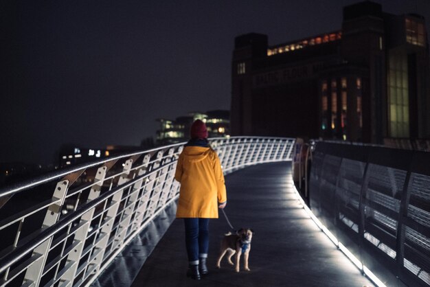 Mujer y perro caminando a través del puente del milenio por la noche por detrás