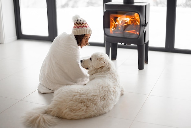 Mujer con perro en casa con chimenea durante el invierno