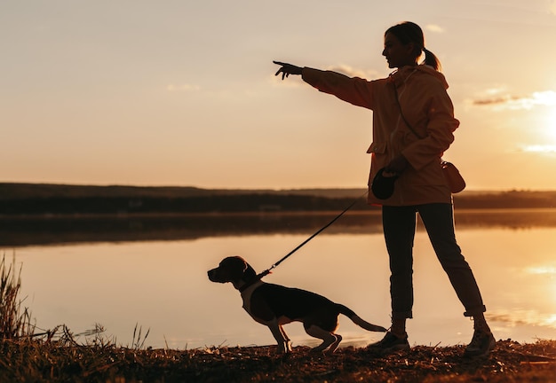 Mujer con perro cerca del lago por la noche