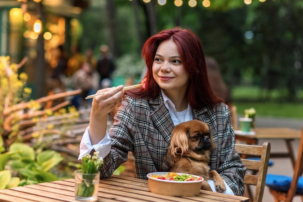 Una mujer con perro comiendo un poke en un parque