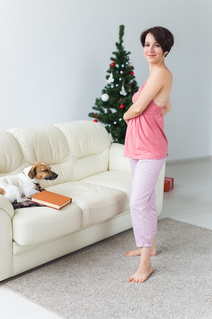 Mujer con perro encantador en salón con árbol de navidad