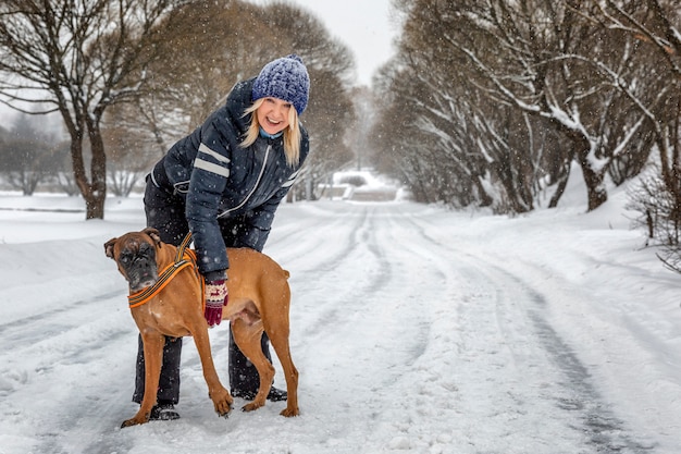 Mujer con un perro jugando en el parque de invierno. Amor y ternura.