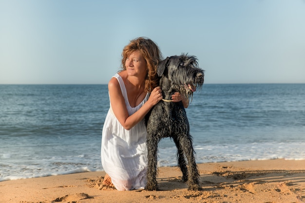 Mujer con perro en la orilla del mar mirando el paisaje