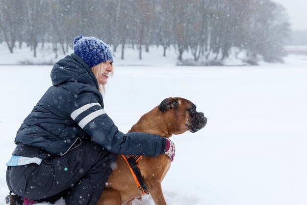 Mujer con un perro en un paseo en tiempo nevoso