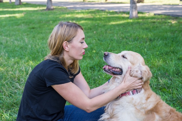 Mujer y perro perdiguero sobre un fondo de hierba verde en el parque. Una mujer se comunica con su perro al aire libre.