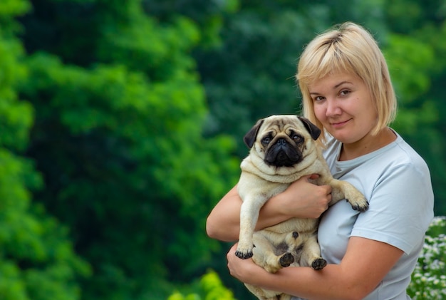 Mujer con un perro pug en brazos.