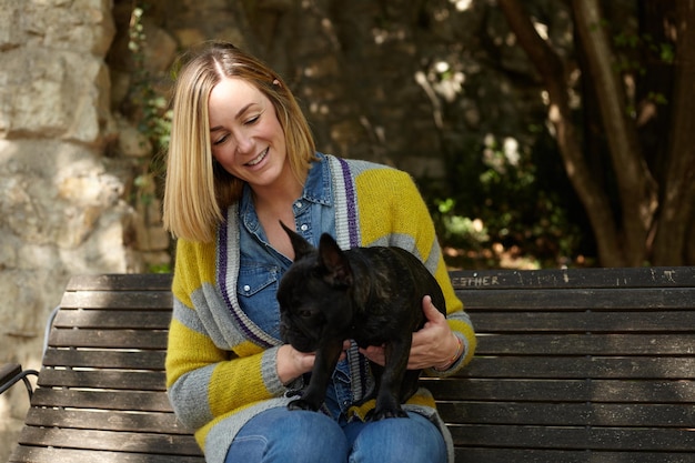 Foto mujer con perro sentada en un banco en el parque