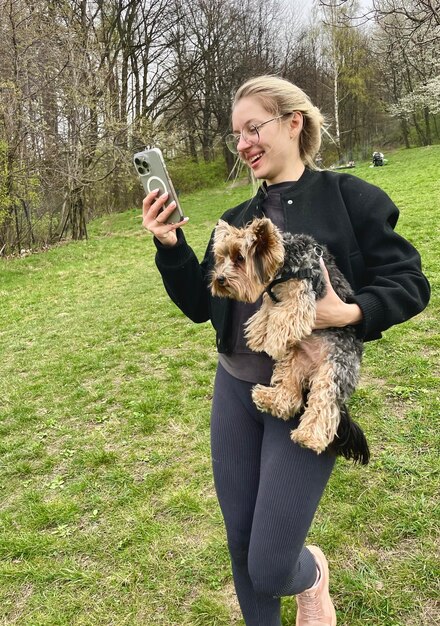 una mujer con un perro y un teléfono celular en la mano