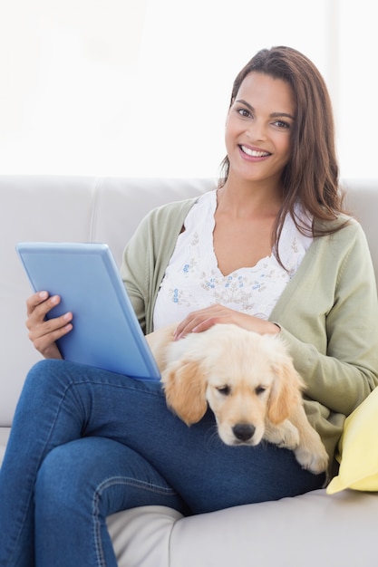 Mujer con perro usando la tableta en el sofá