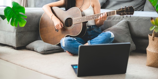 Mujer persona tocando guitarra acústica instrumento musical en casa joven músico asiático estilo de vida