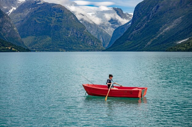 Mujer pescando en un barco. Hermoso paisaje natural de la naturaleza Noruega. lago lovatnet valle de Lodal.