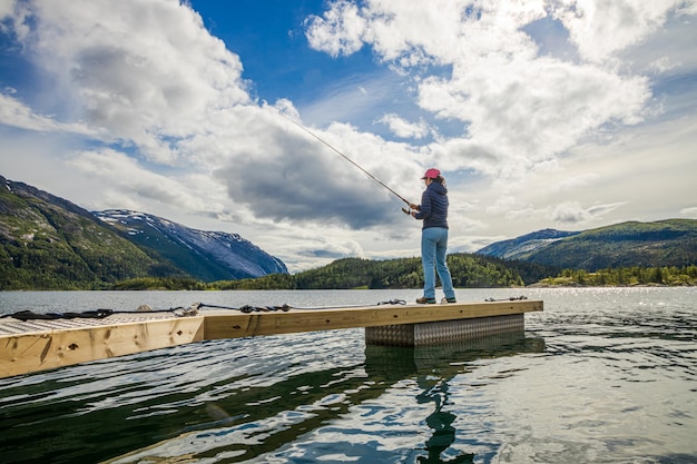 Mujer pescando en caña de pescar girando en Noruega. La pesca en Noruega es una forma de adoptar el estilo de vida local. Innumerables lagos y ríos y una extensa costa significa oportunidades excepcionales ...