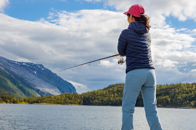 Mujer pescando en caña de pescar girando en Noruega. La pesca en Noruega es una forma de adoptar el estilo de vida local. Innumerables lagos y ríos y una extensa costa significa oportunidades excepcionales ...