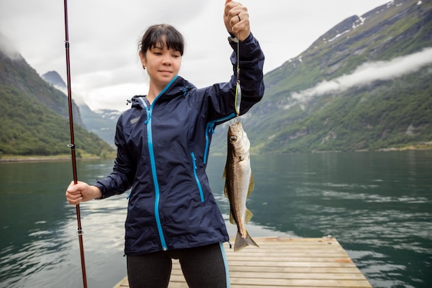 Mujer pescando en caña de pescar girando en Noruega. La pesca en Noruega es una forma de adoptar el estilo de vida local. Innumerables lagos y ríos y una extensa costa significa oportunidades excepcionales ...