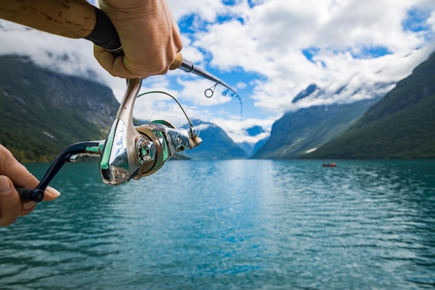 Mujer pescando en caña de pescar girando en Noruega. La pesca en Noruega es una forma de adoptar el estilo de vida local. Innumerables lagos y ríos y una extensa costa significa oportunidades excepcionales ...