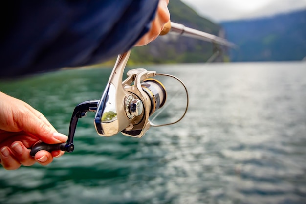 Mujer pescando en caña de pescar girando en Noruega. La pesca en Noruega es una forma de adoptar el estilo de vida local. Innumerables lagos y ríos y una extensa costa significa oportunidades excepcionales ...