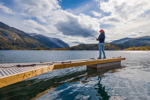 Mujer pescando en Caña de pescar girando en Noruega. Pescar en Noruega es una forma de adoptar el estilo de vida local. Innumerables lagos y ríos y una extensa costa significan excelentes oportunidades...