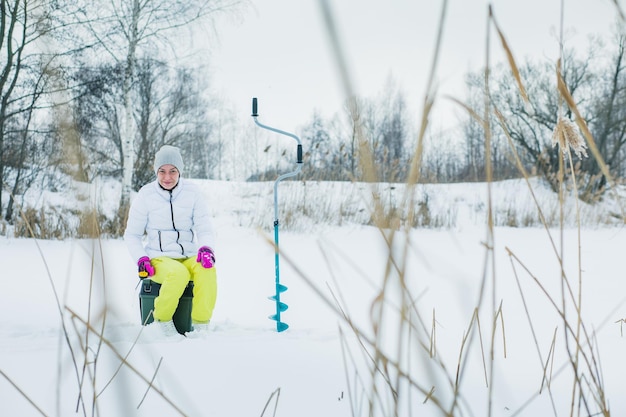 Mujer pescando en el hielo en invierno.