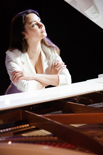 Foto mujer con el piano blanco en el escenario.