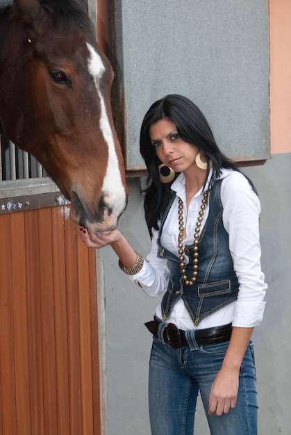 Mujer en el picadero junto a las caballerizas esperando salir a trotar en su caballo